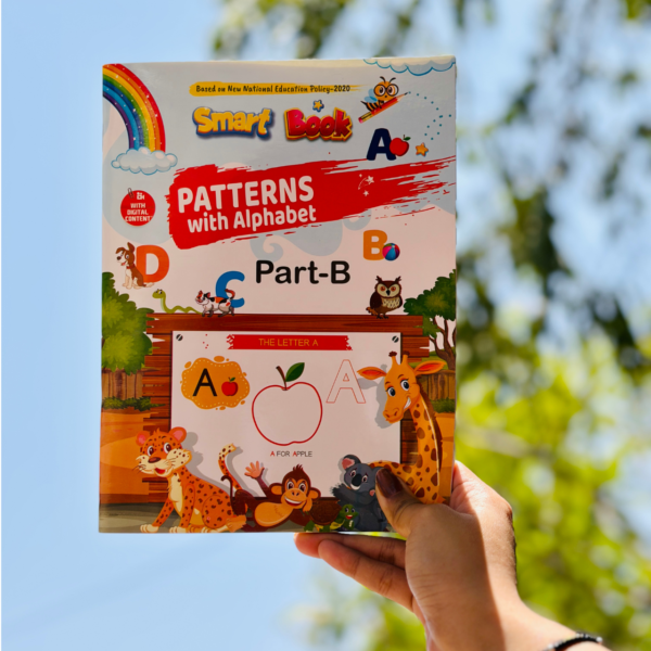 A hand holding up the front cover of Patterns with Alphabet Part-B Beginner against a blurred natural background, showcasing its bright jungle animal theme and "Smart Book" design.